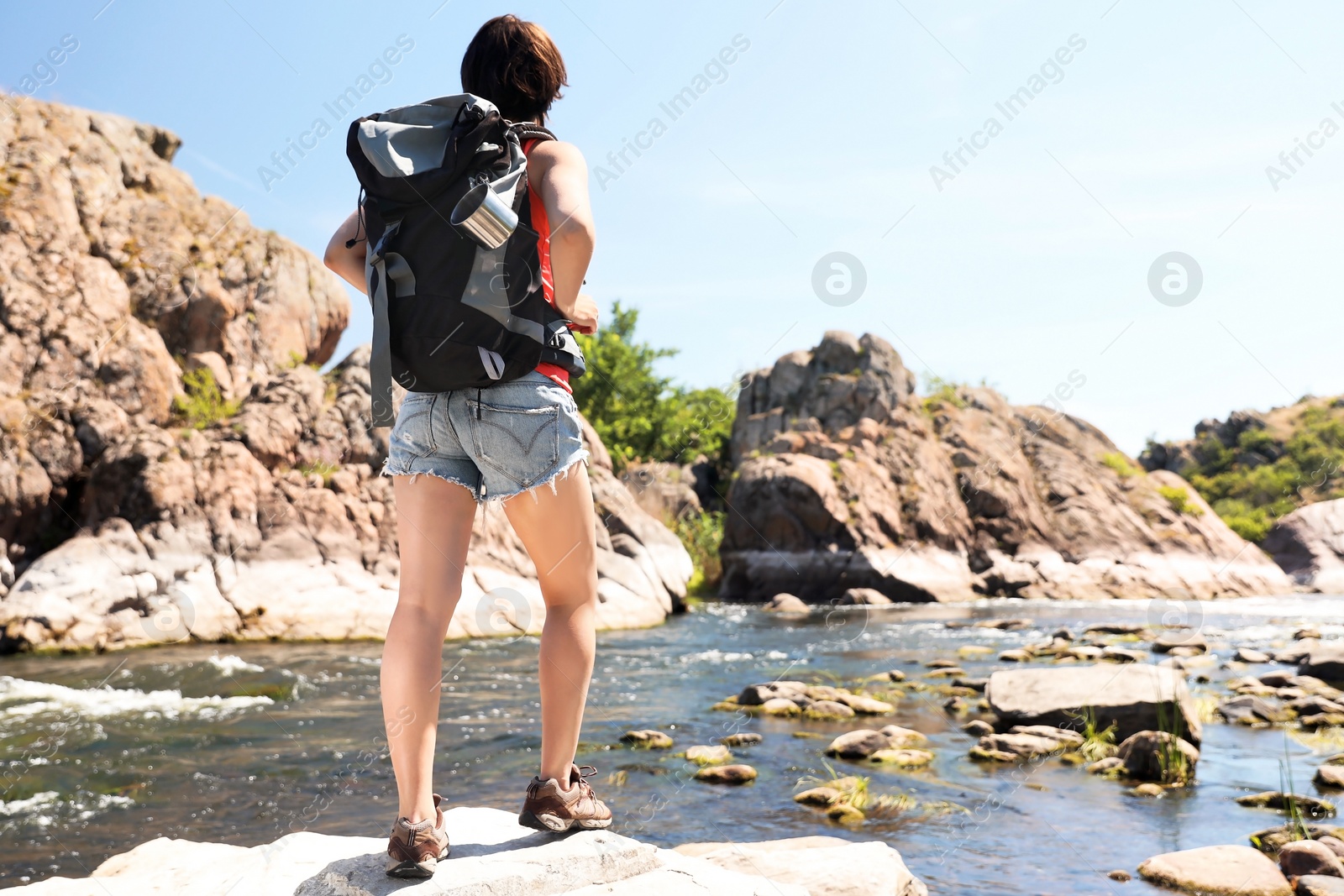 Photo of Young woman on rock near river. Summer camp