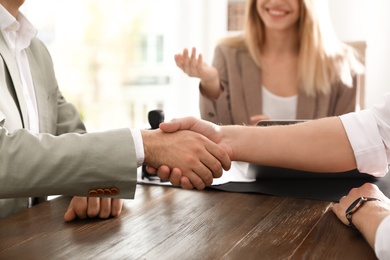 Photo of Business partners shaking hands at table after meeting in office, closeup