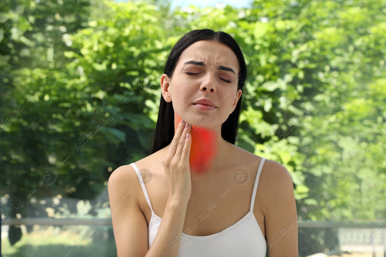 Image of Endocrine system. Woman suffering from pain in thyroid gland near window