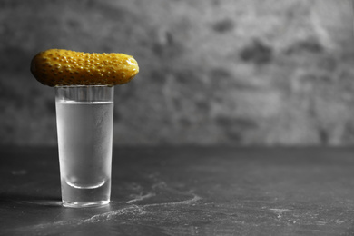 Photo of Cold Russian vodka with pickle on black table. Space for text