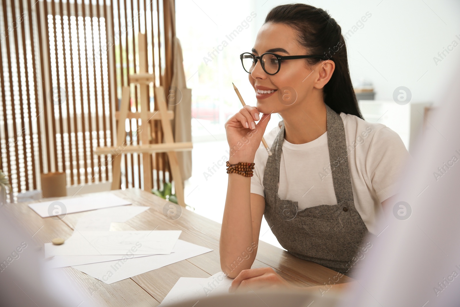 Photo of Young woman drawing with pencil at table indoors. Space for text