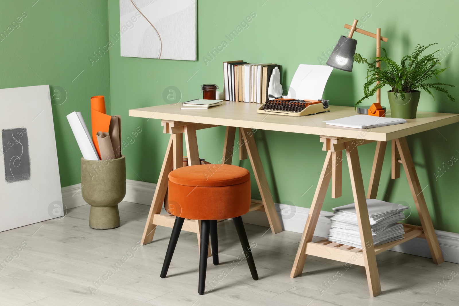 Photo of Writer's workplace with typewriter on wooden desk near pale green wall in room