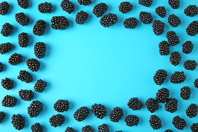 Frame made of tasty blackberries on blue background, top view with space for text