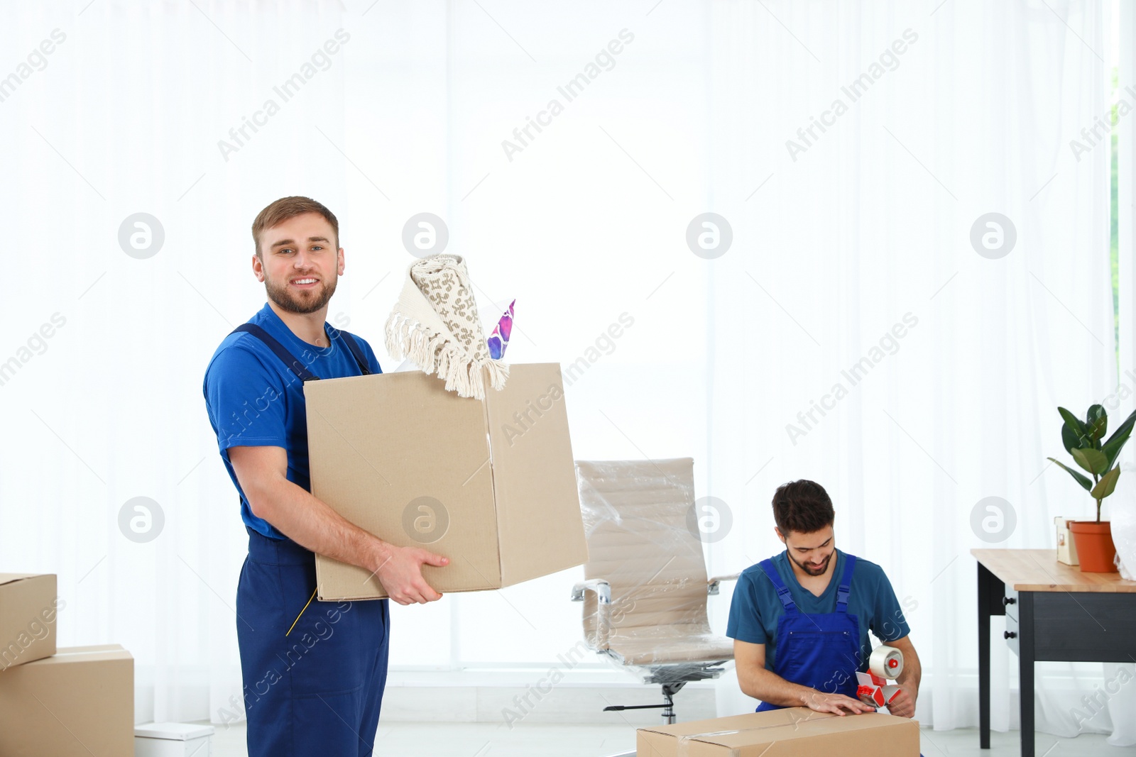 Photo of Young men in uniform working indoors. Moving service