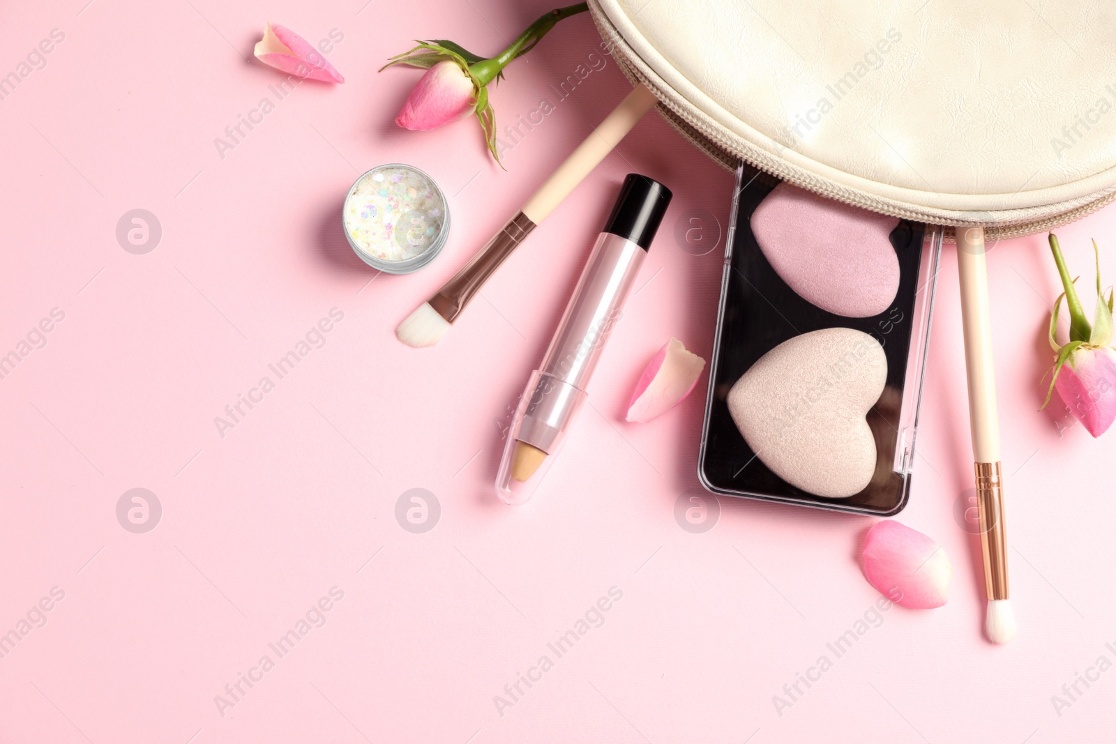 Photo of Set of makeup products with bag and roses on light pink background, flat lay. Space for text