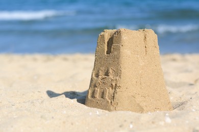 Photo of Beautiful sand castle on beach near sea, space for text