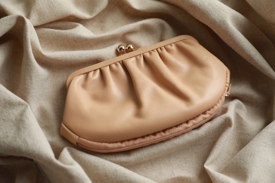 Photo of Stylish presentation of leather purse on beige fabric, closeup