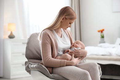 Photo of Mother with her little baby sitting in armchair at home