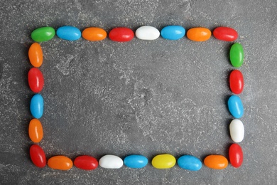 Photo of Frame of jelly beans on stone background, top view. Space for text