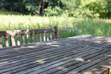 Photo of Empty wooden table with bench on sunny day in garden