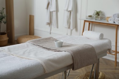 Sea salt for spa procedure and soft terry towels on massage table in salon