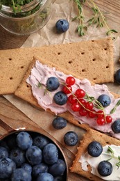Photo of Tasty crispy crackers with cream cheese, thyme and berries, flat lay