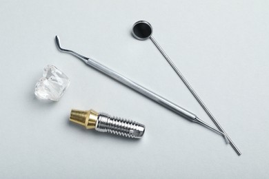 Parts of dental implant and tools on grey background, flat lay
