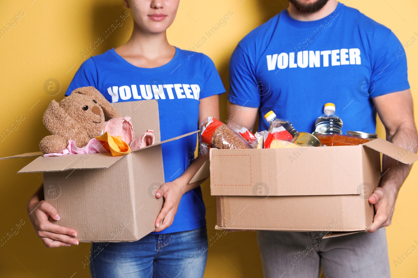 Photo of Young volunteers holding boxes with donations on color background