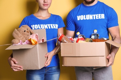 Photo of Young volunteers holding boxes with donations on color background