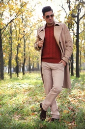 Handsome man walking in park on autumn day