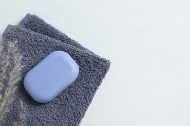 Photo of Soap bar and terry towel on white wooden table, top view. Space for text