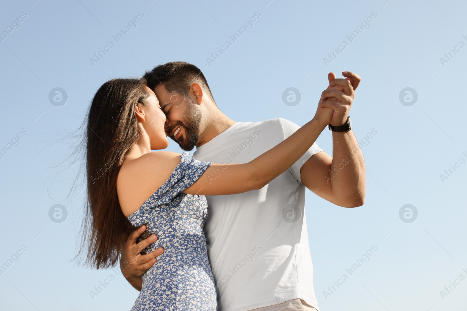 Photo of Romantic date. Beautiful couple spending time together against blue sky, low angle view