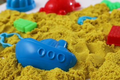 Photo of Bright kinetic sand and toys on table, closeup