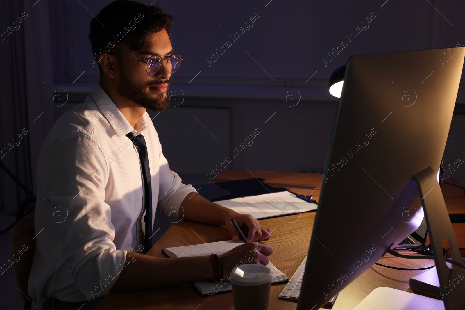 Photo of Tired young man working late in office