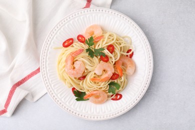 Tasty spaghetti with shrimps, chili pepper and parsley on grey table, top view