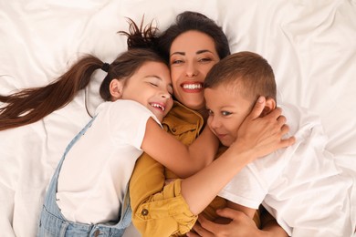 Happy mother with her children on bed, top view