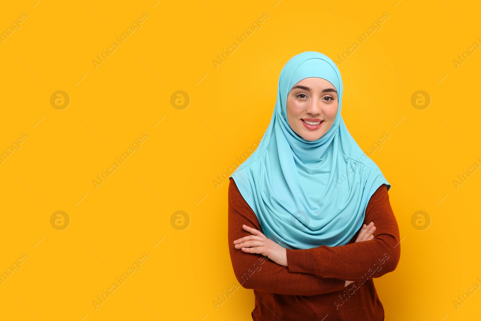 Photo of Portrait of Muslim woman in hijab on orange background, space for text