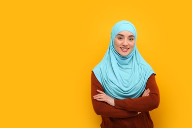Portrait of Muslim woman in hijab on orange background, space for text