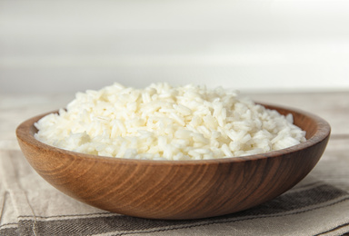 Photo of Wooden bowl with cooked rice on table, closeup
