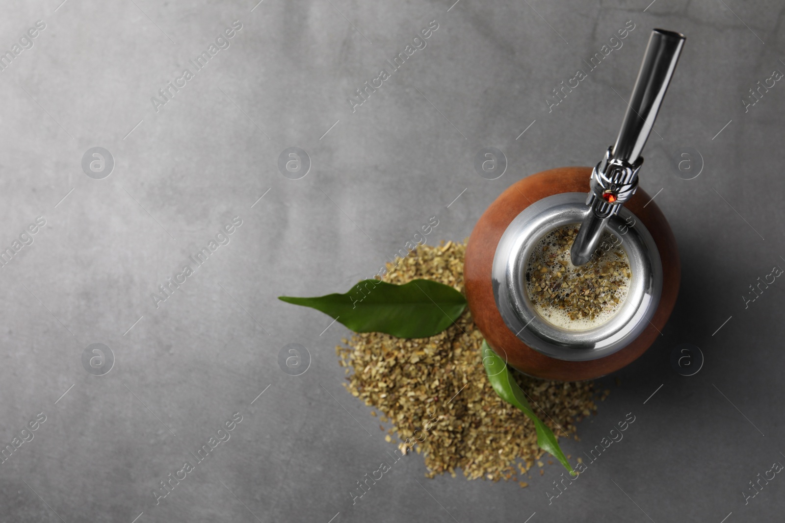 Photo of Calabash with mate tea and bombilla on light grey table, flat lay. Space for text