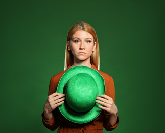 Photo of Young woman with green hat on color background. St. Patrick's Day celebration