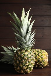 Photo of Fresh ripe juicy pineapples on wooden table