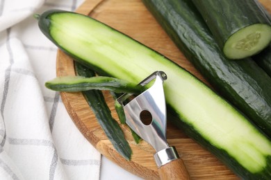 Photo of Fresh cucumbers and peeler on table, above view