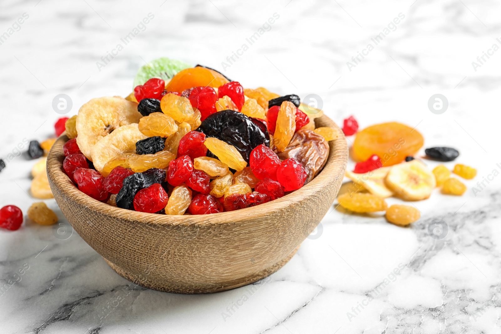 Photo of Bowl with different dried fruits on marble background. Healthy lifestyle
