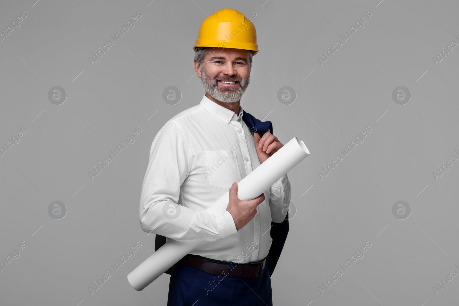 Photo of Architect in hard hat holding draft on grey background