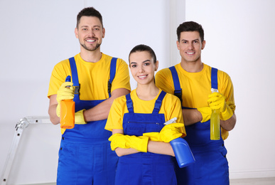 Team of professional janitors with cleaning supplies indoors