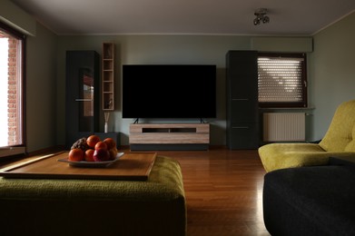 Photo of Stylish room with beautiful furniture and TV set on table. Interior design