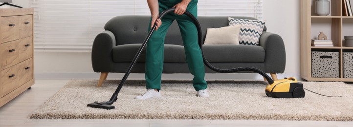 Dry cleaner's employee hoovering carpet with vacuum cleaner in room, closeup. Banner design