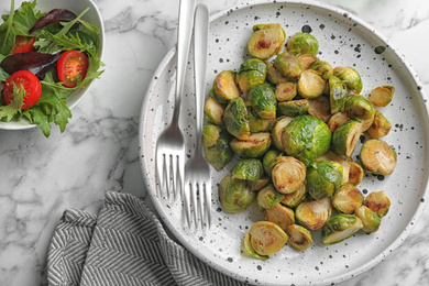 Delicious roasted brussels sprouts on white marble table, flat lay