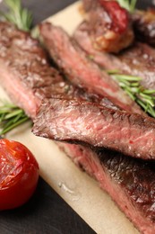 Photo of Delicious grilled beef with rosemary and tomato on table, closeup