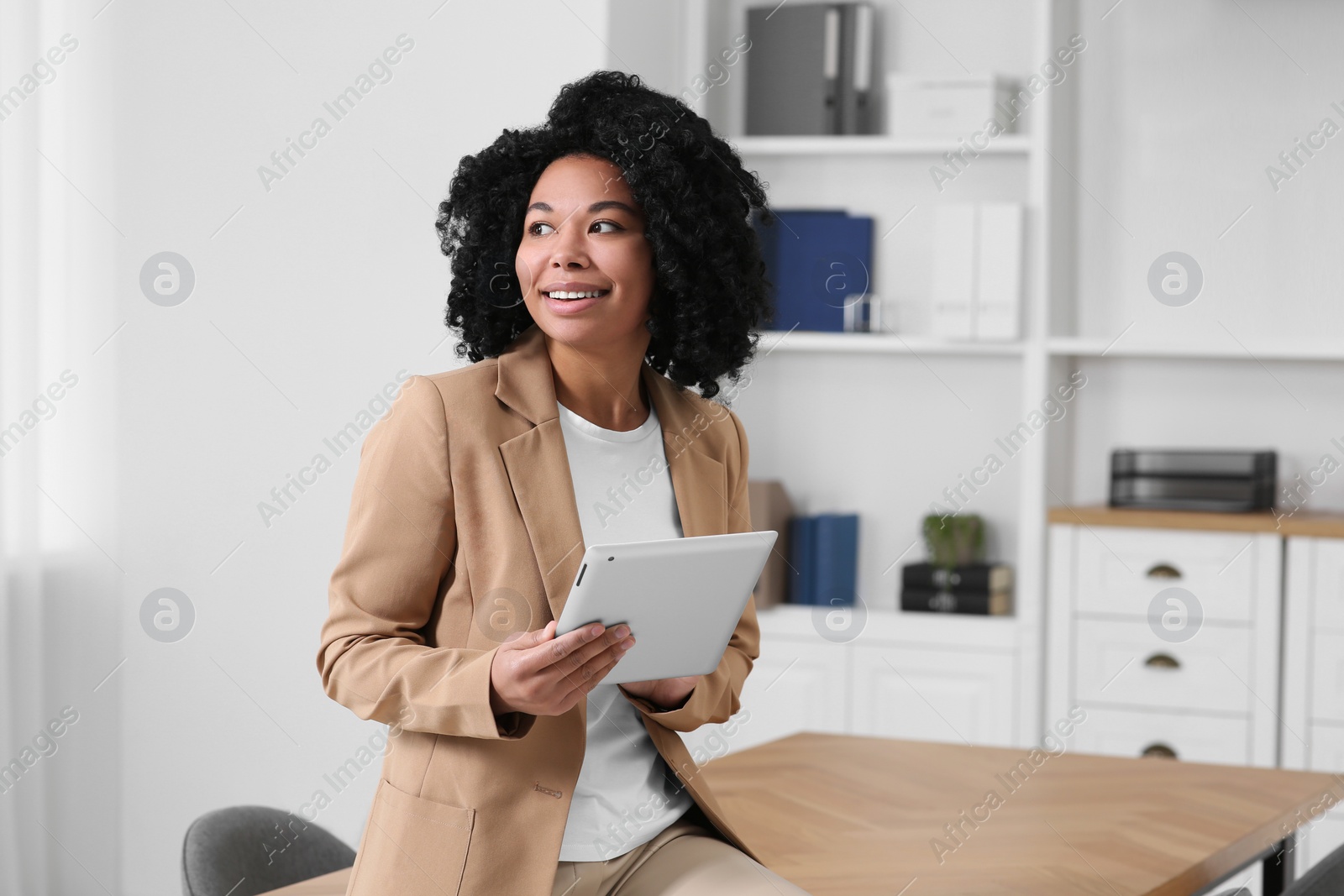 Photo of Smiling young businesswoman using tablet in modern office