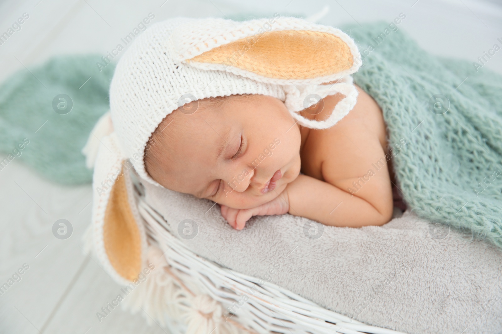 Photo of Adorable newborn child wearing bunny ears hat in baby nest