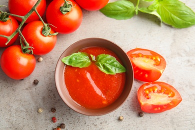 Flat lay composition with bowl of sauce and tomatoes on grey table