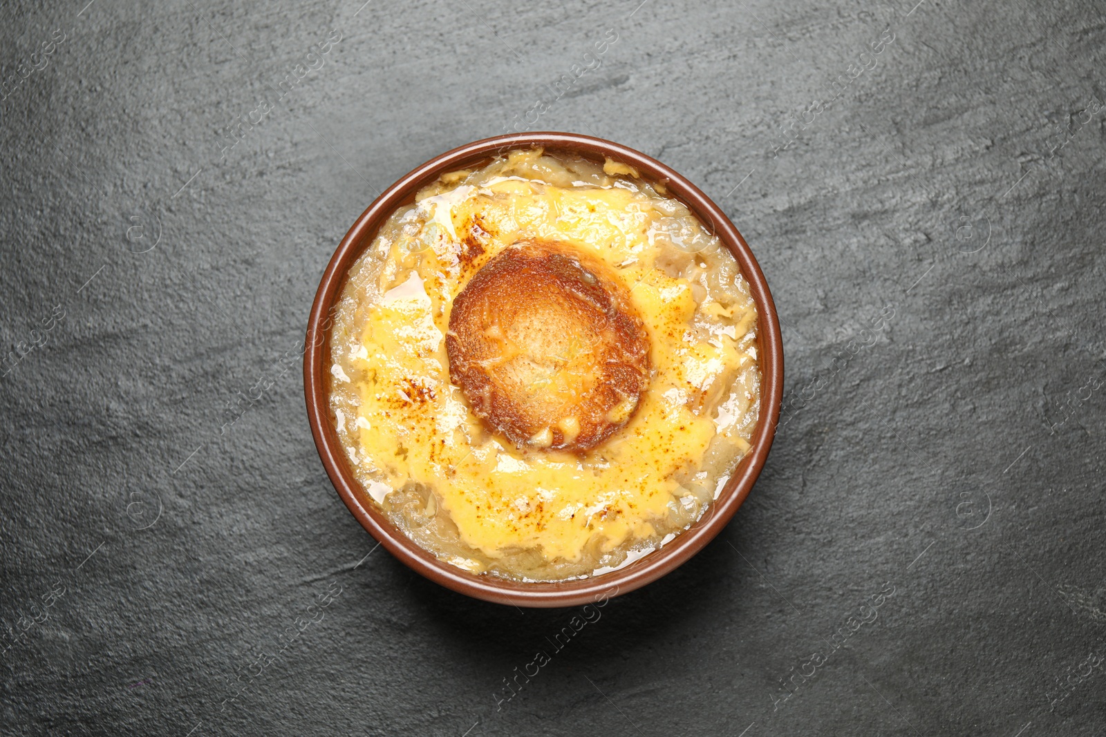 Photo of Tasty homemade french onion soup on black table, top view