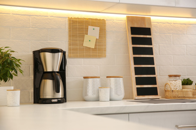 Photo of Modern coffeemaker on countertop near brick wall in kitchen