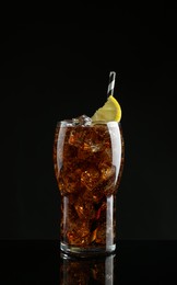 Glass of refreshing soda water with ice cubes and lemon slice on black background