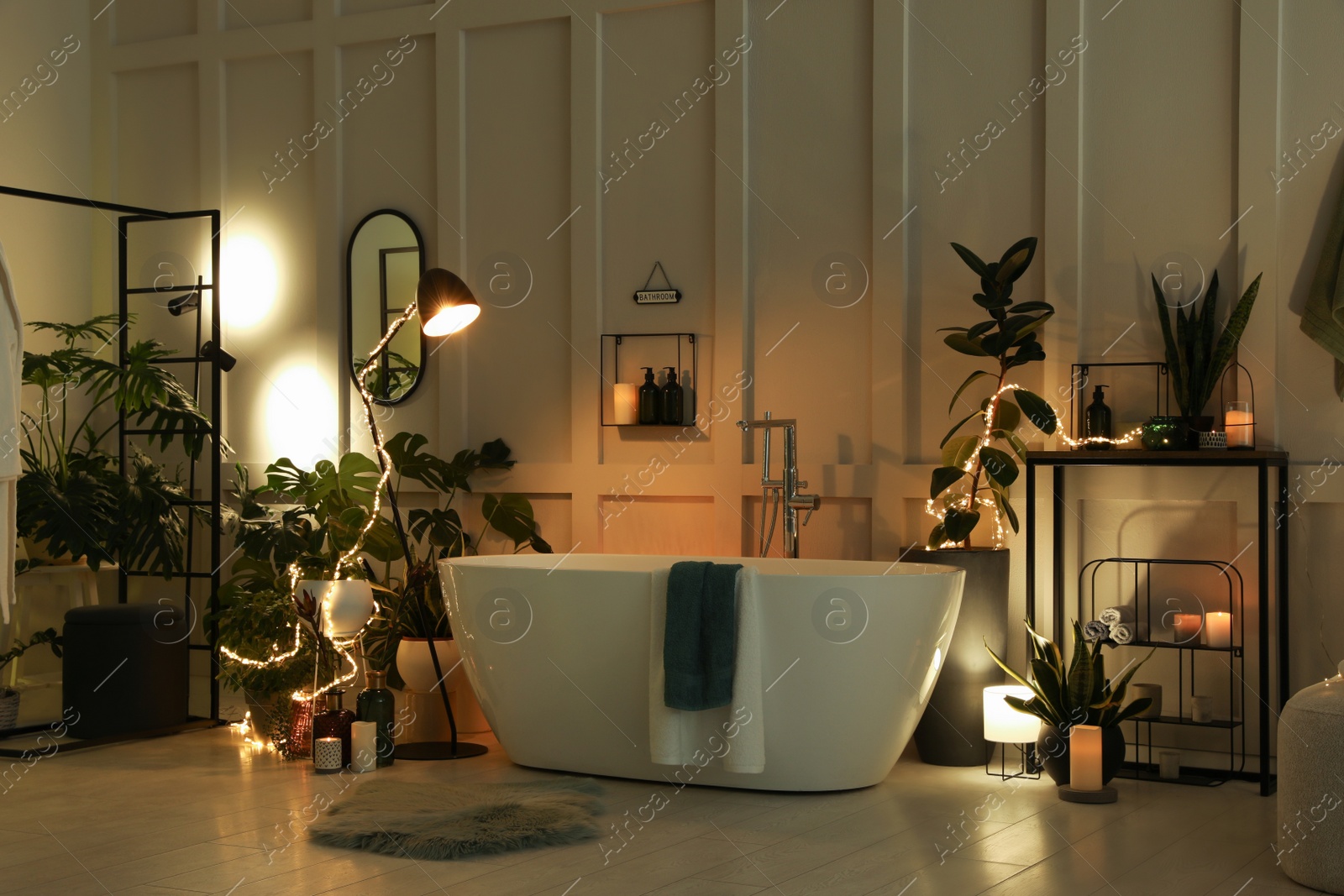 Photo of Stylish bathroom interior with houseplants and string lights. Home design