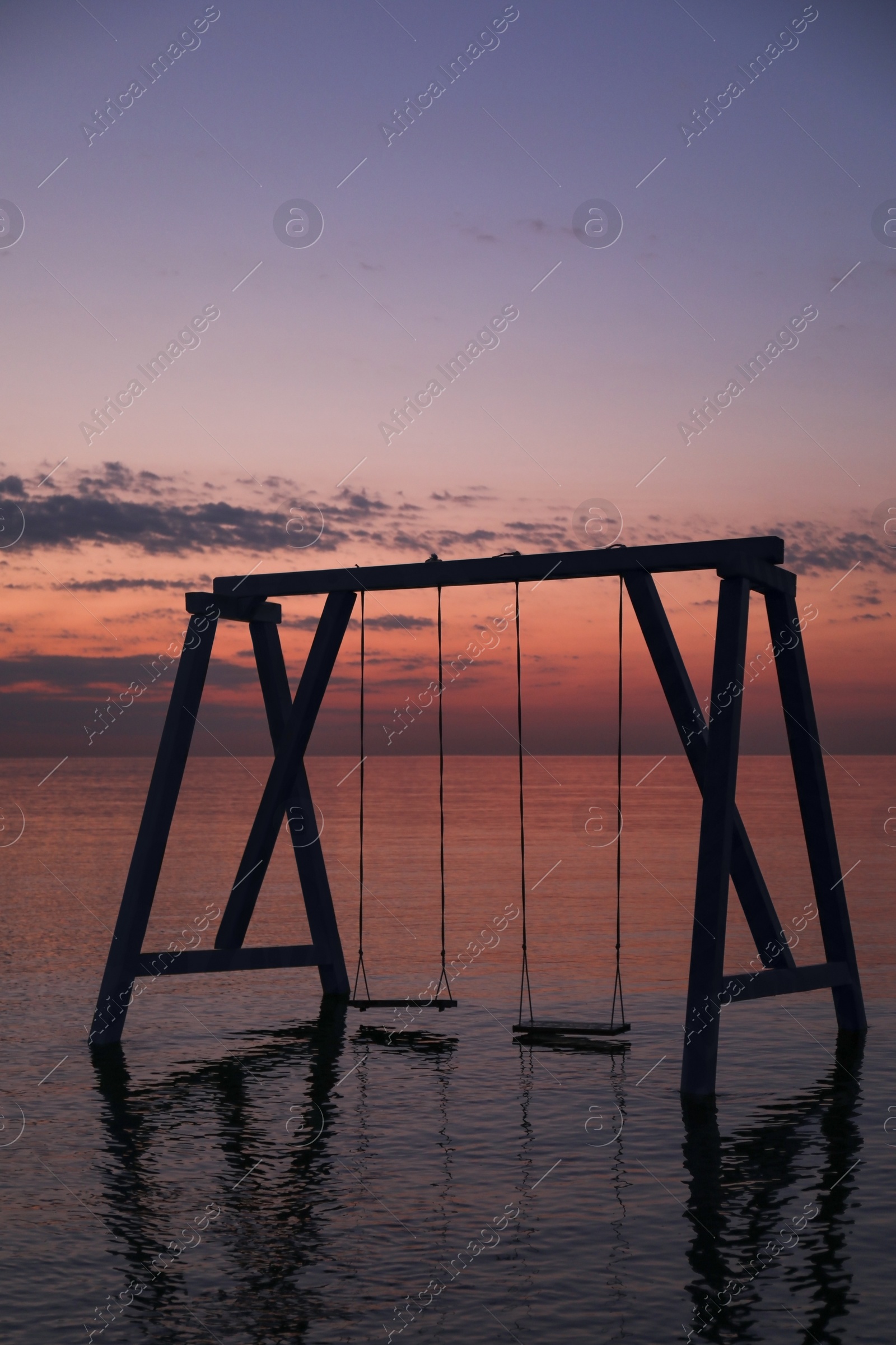 Photo of Picturesque view of swing in water on sunrise