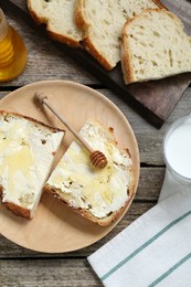 Slices of bread with butter, honey and milk on wooden table, flat lay