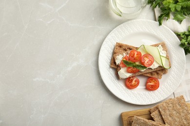 Photo of Fresh rye crispbreads with cream cheese and vegetables on light grey marble table, flat lay. Space for text